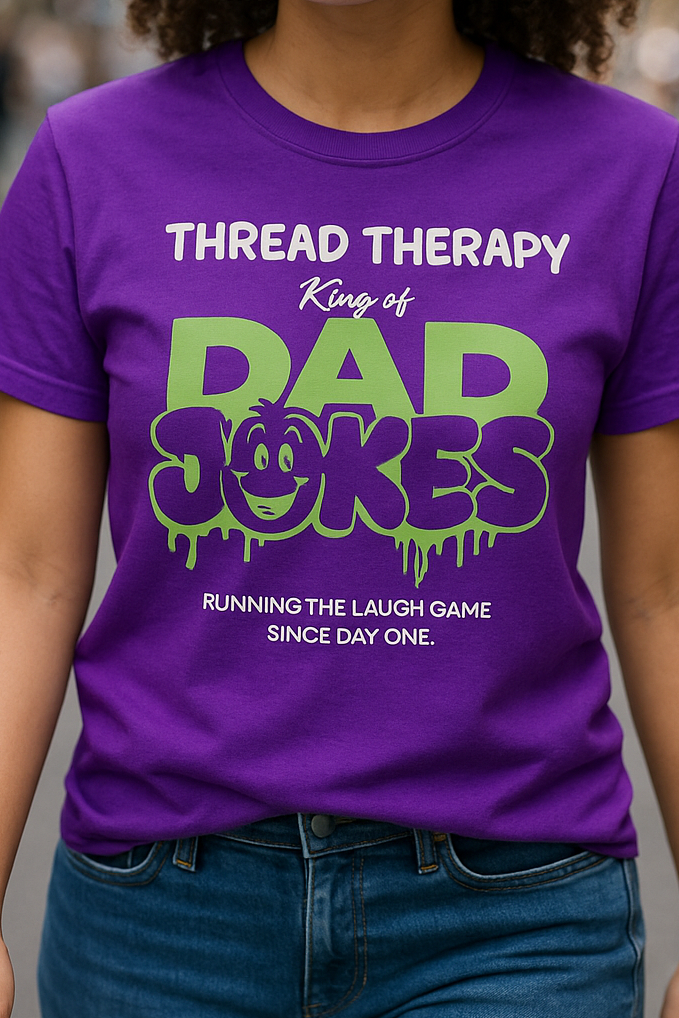 Person wearing a purple t-shirt with 'Thread Therapy King of Dad Jokes' text design.